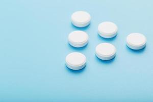 White medicinal tablets in the shape of a pyramid on a blue background. photo