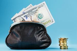 Black wallet with coins and dollars on a blue background. photo