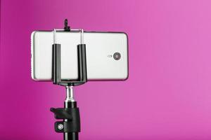 Smartphone on a tripod as a photo-video camera on a pink background. Record videos and photos for your blog.