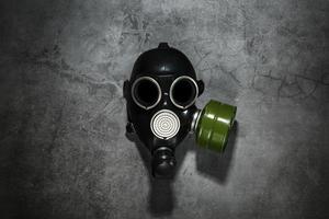 Gas mask on a black stone background with a green filter cartridge. Post-apocalyptic concept. photo