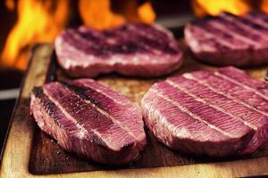 Grilled steaks on an old cutting board with flames in the background. photo