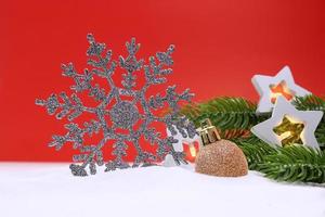 Silver sparkling snowflake with star lanterns and green spruce branches and shiny balls on red background. Christmas, New Year. Copy space photo