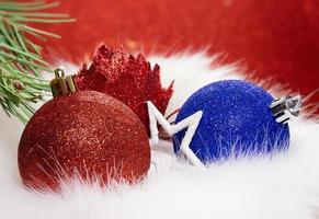 Red, blue shiny ball and flower with star with fir branch on fur from behind blurred background. Christmas, New Year. Copy space photo