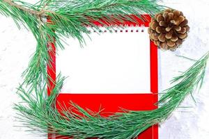 papel blanco en blanco para texto con rama de abeto y cono marrón sobre fondo blanco nevado. imagen de navidad y año nuevo. hoja de negocios. buzón rojo. copie el espacio foto