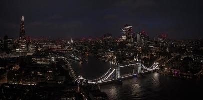 Aerial view to the illuminated Tower Bridge and skyline of London, UK photo