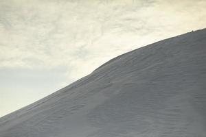 Mountain of snow. Snowy slope. Slide against sky. photo