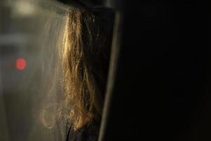 Girl sits by glass on bus. Hair for girl by window. Inside bus. Passenger in transport. photo