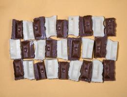 Slices of black and white chocolate on a beige background. Slices from a bar of chocolate. photo