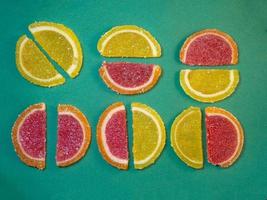 Fruit jelly in the form of orange slices on a green surface. Background from sweets. photo