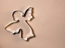 a baking dish in an angel's shape lies on a pink material. photo