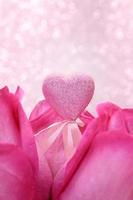 Shiny pink heart between red roses with defocused lights. Holiday, Valentine's, International Women's and Mother's Day, March 8, Birthday. Copy space photo
