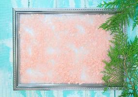 Frame with textured pink background on blue with branch of green thuja. Winter. Christmas, new year. Copy space photo