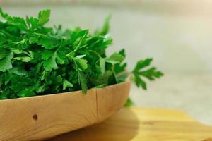 parsley, cilantro in a wooden plate on the table. Background soft focus. Ingredient for cooking photo