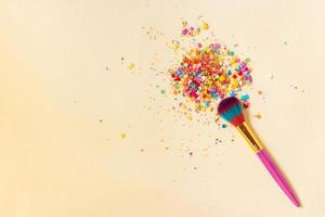 Makeup brush with bright sweets and confetti on a yellow background. Festive and creative background. Copy space photo