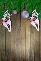 Two white deer and silver sparkling balls with glitter on wooden background with branches of Christmas tree. New Year. Copy space photo