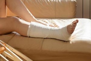 Bandaged leg cast and toes after a running injury accident. Teen girl in a plaster cast. Cropped shot of a girl. Shin splints. photo