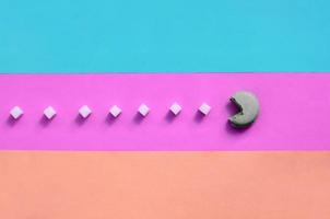 A composition of macaroon with an open mouth that is going to eat sugar cubes on a pink, lime, blue and coral background photo