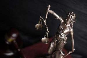 The Statue of Justice - lady justice or justitia the Roman goddess of Justice. Statue on brown book with judge gavel. Concept of judicial trial, courtroom process and lawyers work photo