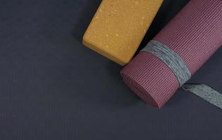 top view yoga mat roll on black rubber background, Purple yoga mat placed on the floor to prepare for exercise, fitness equipment background concept photo