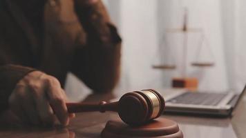 Justice and law concept.Male judge in a courtroom with the gavel, working with, computer and docking keyboard, eyeglasses, on table in morning light video