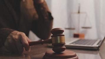 Justice and law concept.Male judge in a courtroom with the gavel, working with, computer and docking keyboard, eyeglasses, on table in morning light video