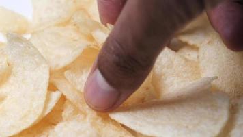 Close up of plain potato chips as a hand grabs some video