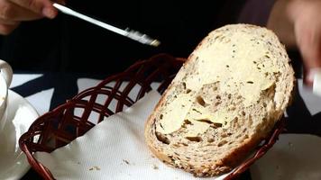 Diner spreads sof butter on thick slice of seeded bread video