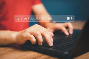 Football fan's hand working with computer laptop on desk in home. Searching Browsing Internet Data Information with search bar. Search Engine technology networking Concept. photo