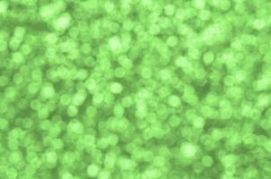 Blurred lime green decorative sequins. Background image with shiny bokeh lights from small elements photo