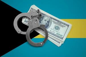 Bahamas flag  with handcuffs and a bundle of dollars. Currency corruption in the country. Financial crimes photo