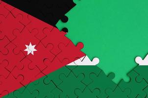 Jordan flag  is depicted on a completed jigsaw puzzle with free green copy space on the right side photo