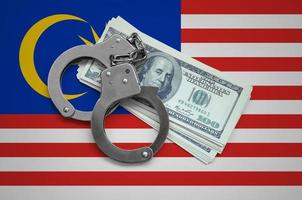 Malaysia flag  with handcuffs and a bundle of dollars. Currency corruption in the country. Financial crimes photo