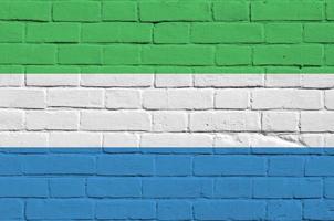 Sierra Leone flag depicted in paint colors on old brick wall. Textured banner on big brick wall masonry background