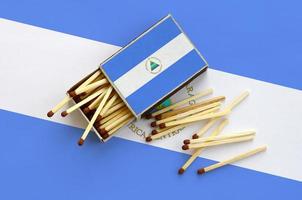 Nicaragua flag  is shown on an open matchbox, from which several matches fall and lies on a large flag photo