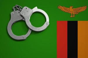 Zambia flag  and police handcuffs. The concept of crime and offenses in the country photo