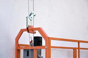 Hoist supply and safety lock as part of suspended wire rope platform for facade works on high multistorey buildings. Hoist for elevation, raising or lifting cradle photo