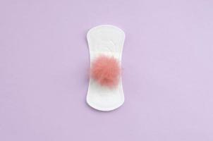 Menstrual pad and red fluffy fuzzy as a blood on violet pastel background flat lay top view photo