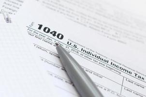 The pen and notebook is lies on the tax form 1040 U.S. Individual Income Tax Return. The time to pay taxes photo