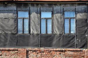 vieja pared de ladrillo desgastada con ventanas foto