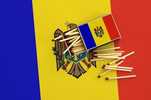Moldova flag  is shown on an open matchbox, from which several matches fall and lies on a large flag photo