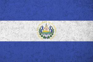 El Salvador flag depicted in bright paint colors on old relief plastering wall. Textured banner on rough background photo