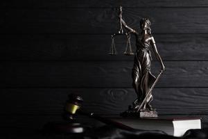 The Statue of Justice - lady justice or justitia the Roman goddess of Justice. Statue on brown book with judge gavel. Concept of judicial trial, courtroom process and lawyers work photo