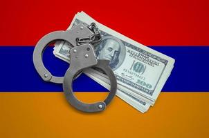 Armenia flag  with handcuffs and a bundle of dollars. Currency corruption in the country. Financial crimes photo