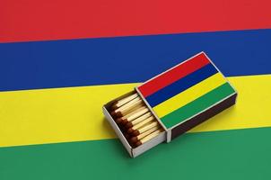 Mauritius flag  is shown in an open matchbox, which is filled with matches and lies on a large flag photo