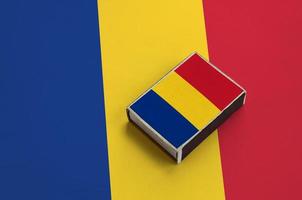 Romania flag  is pictured on a matchbox that lies on a large flag photo