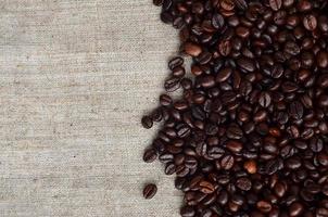 Texture of a gray canvas made of old and coarse burlap with coffee beans on it photo