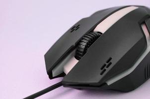 Closeup of a black gaming optical mouse on a pink background photo