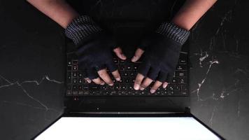 visão aérea das mãos em luvas sem dedos digitando em um teclado de laptop preto video
