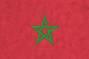 Morocco flag depicted in bright paint colors on old relief plastering wall. Textured banner on rough background photo