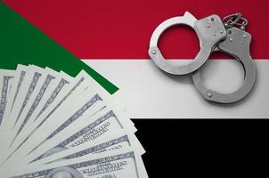 Sudan flag  with handcuffs and a bundle of dollars. The concept of illegal banking operations in US currency photo